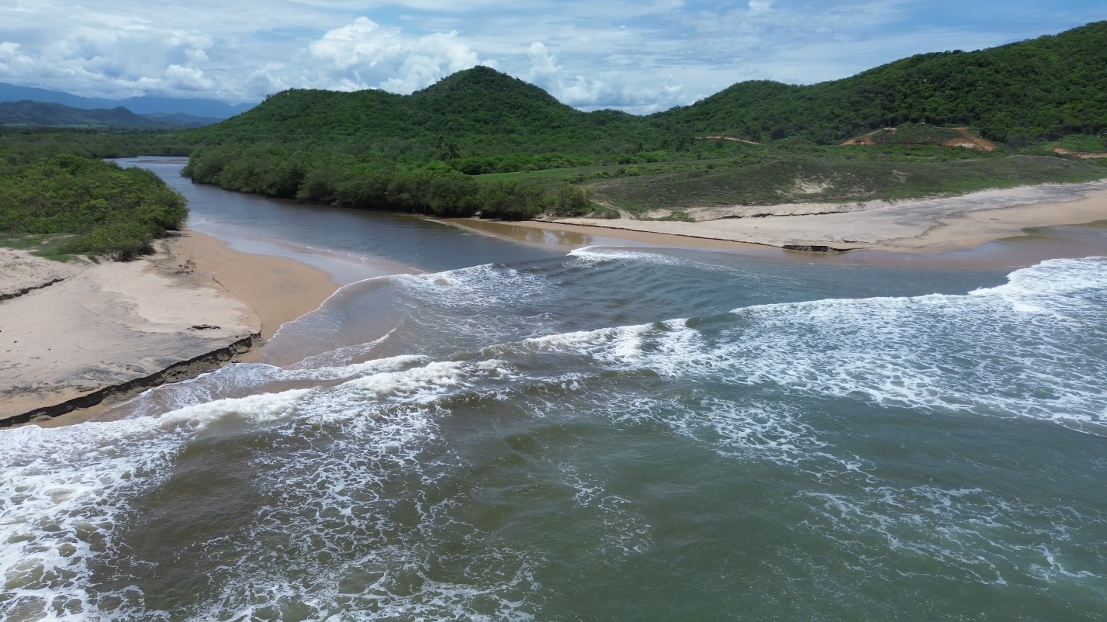 Olas del océano encontrándose con las aguas del río en la playa